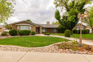 Ranch-style home with a front yard, stucco siding, and a chimney