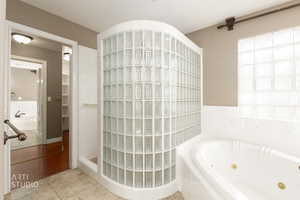 Bathroom featuring a jetted tub, light tile patterned floors, and tiled shower