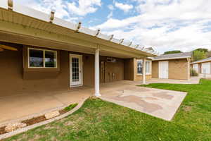 Rear view of house featuring stucco siding, a patio, and a lawn
