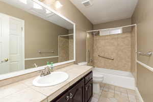 Bathroom featuring vanity, shower / washtub combination, light tile patterned floors, and a textured ceiling