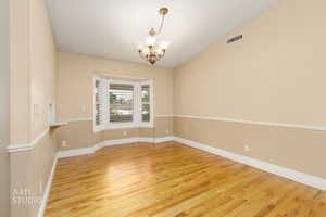 Unfurnished dining area featuring a chandelier and light wood finished floors