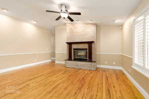 Unfurnished living room featuring a fireplace, a ceiling fan, light wood finished floors, and vaulted ceiling