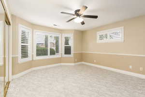 Empty room featuring light colored carpet, plenty of natural light, and ceiling fan