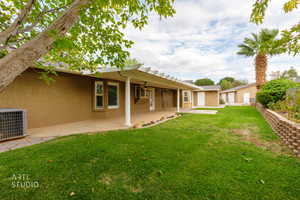 Back of house with stucco siding, a patio area, a yard, and a ceiling fan