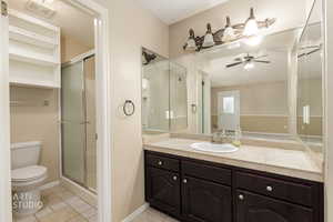 Full bath featuring light tile patterned floors, vanity, a shower stall, ceiling fan, and a textured ceiling