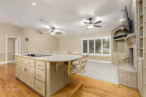 Kitchen with a kitchen bar, a center island, light wood finished floors, cream cabinetry, and ceiling fan