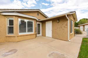 Rear view of property with a patio area, stucco siding, and a gate