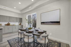 Dining room with recessed lighting, light wood-style flooring, and a tray ceiling