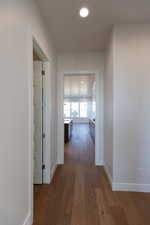 Hallway with dark wood-type flooring and baseboards