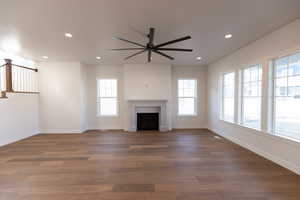 Unfurnished living room featuring ceiling fan, dark wood-type flooring, a fireplace, and recessed lighting