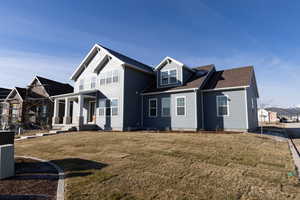 Rear view of house with a porch, a yard, and roof with shingles