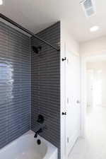 Bathroom featuring shower / tub combination, recessed lighting, a textured ceiling, and light tile patterned floors