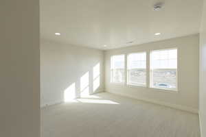 Empty room featuring light colored carpet, recessed lighting, a textured ceiling, and a smoke detector