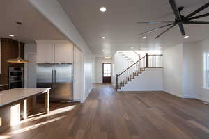Kitchen featuring stainless steel appliances, dark wood-style flooring, hanging light fixtures, open floor plan, and white cabinetry