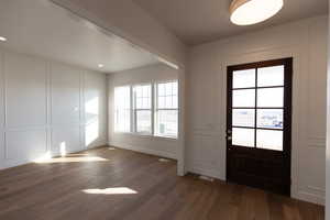 Entrance foyer with a decorative wall and dark wood-type flooring