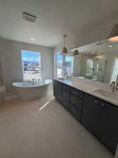 Full bath featuring a shower stall, double vanity, a textured ceiling, a freestanding tub, and light tile patterned floors