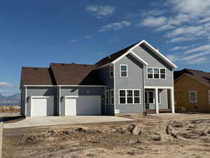View of front of house with a garage, concrete driveway, a patio area, and roof with shingles