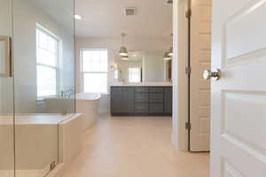 Full bath featuring double vanity, a soaking tub, healthy amount of natural light, recessed lighting, and a shower stall