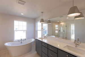 Full bathroom with a soaking tub, a stall shower, double vanity, recessed lighting, and a textured ceiling