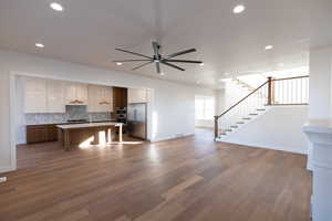 Kitchen with open floor plan, light countertops, two tone cabinets, a center island, and stainless steel appliances