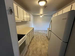 White electric stove, refrigerator, and overhead lighting.