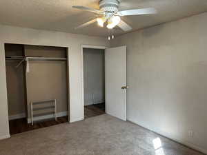 Unfurnished bedroom featuring a textured ceiling, carpet floors, ceiling fan, and a closet