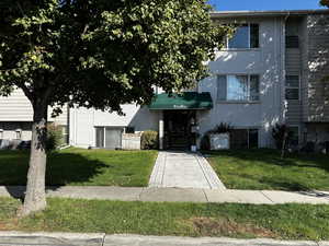 Front entrance of Woodcrest Condominiums with mature tree, landscaped walkway, and secure building access.