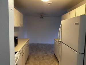Clean and functional kitchen with light countertops, white cabinetry, and white appliances.