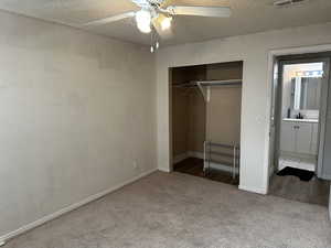 Primary bedroom featuring a textured ceiling, carpet floors, ceiling fan, and closet.