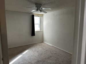 Primary bedroom featuring a textured ceiling, carpet floors, ceiling fan, and closet.