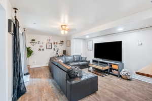 Living room featuring light wood-style flooring, ceiling fan, and a barn door