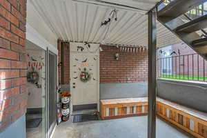 Doorway to property with brick siding and a patio