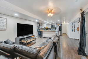 Living room with wood finished floors, recessed lighting, and a ceiling fan