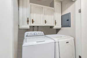 Laundry area featuring electric panel, cabinet space, and independent washer and dryer