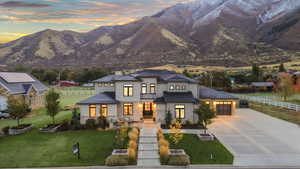 View of front of property featuring driveway, stucco siding, stone siding, a garage, and a chimney