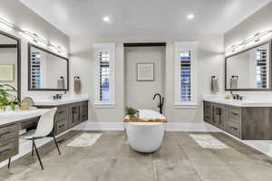 Bathroom with two vanities, a freestanding tub, and recessed lighting