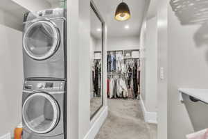 Washroom featuring light carpet and stacked washing machine and dryer