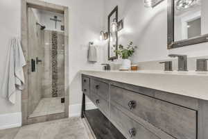 Full bathroom with double vanity, light tile patterned flooring, and a shower stall