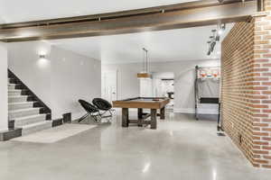 Recreation room featuring concrete flooring, pool table, and brick wall