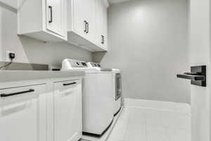 Laundry area featuring light tile patterned floors, separate washer and dryer, and cabinet space