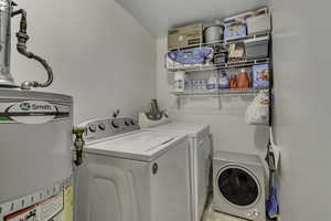 Washroom featuring water heater and separate washer and dryer