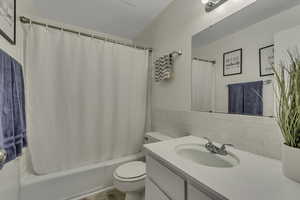 Bathroom featuring tile walls, vanity, shower / tub combo, and light tile patterned floors