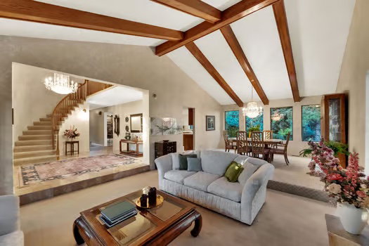 Living room featuring a chandelier, carpet floors, stairs and dramatic vaulted beamed ceilings.