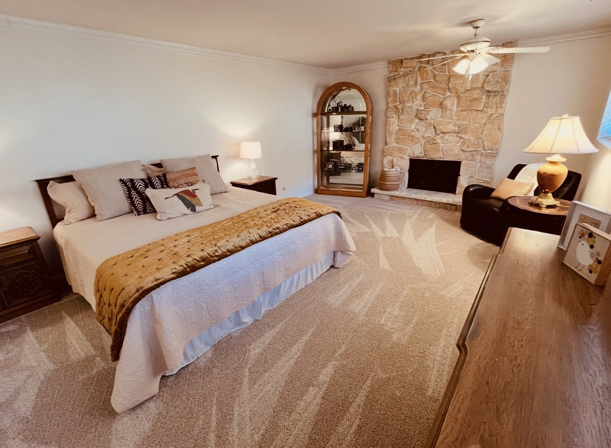 Bedroom with New carpeting, LOTS of extra space for sitting area by the custom stone fireplace, and ceiling fan too!