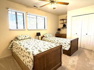Bedroom with light carpet, ceiling fan, Double-wide closet & built-in desk