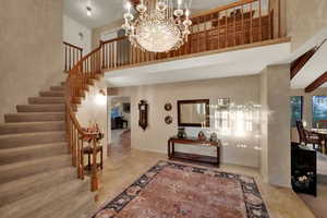 Stunning entryway with towering ceiling, elegant stairs, and a classic chandelier