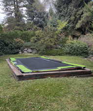 View of lower back yard with a portion of it sporting a functional built-in trampoline