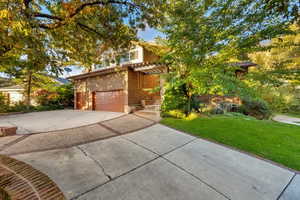View of front of property featuring a front yard, driveway, a garage, and stucco siding