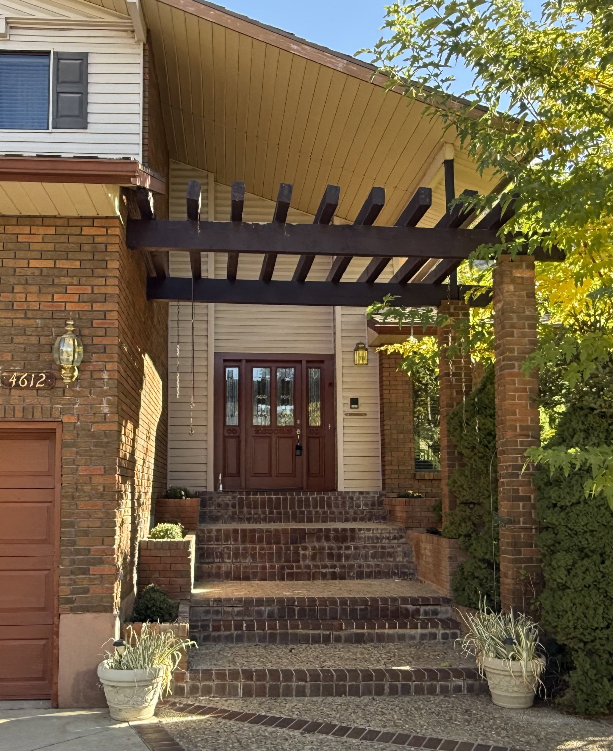 Beautiful shaded front door entry featuring brick stairs and built-in flower planters