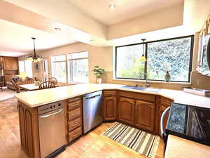 Kitchen with stainless steel appliances, light countertops, wood finish cabinetry, a peninsula, and a chandelier